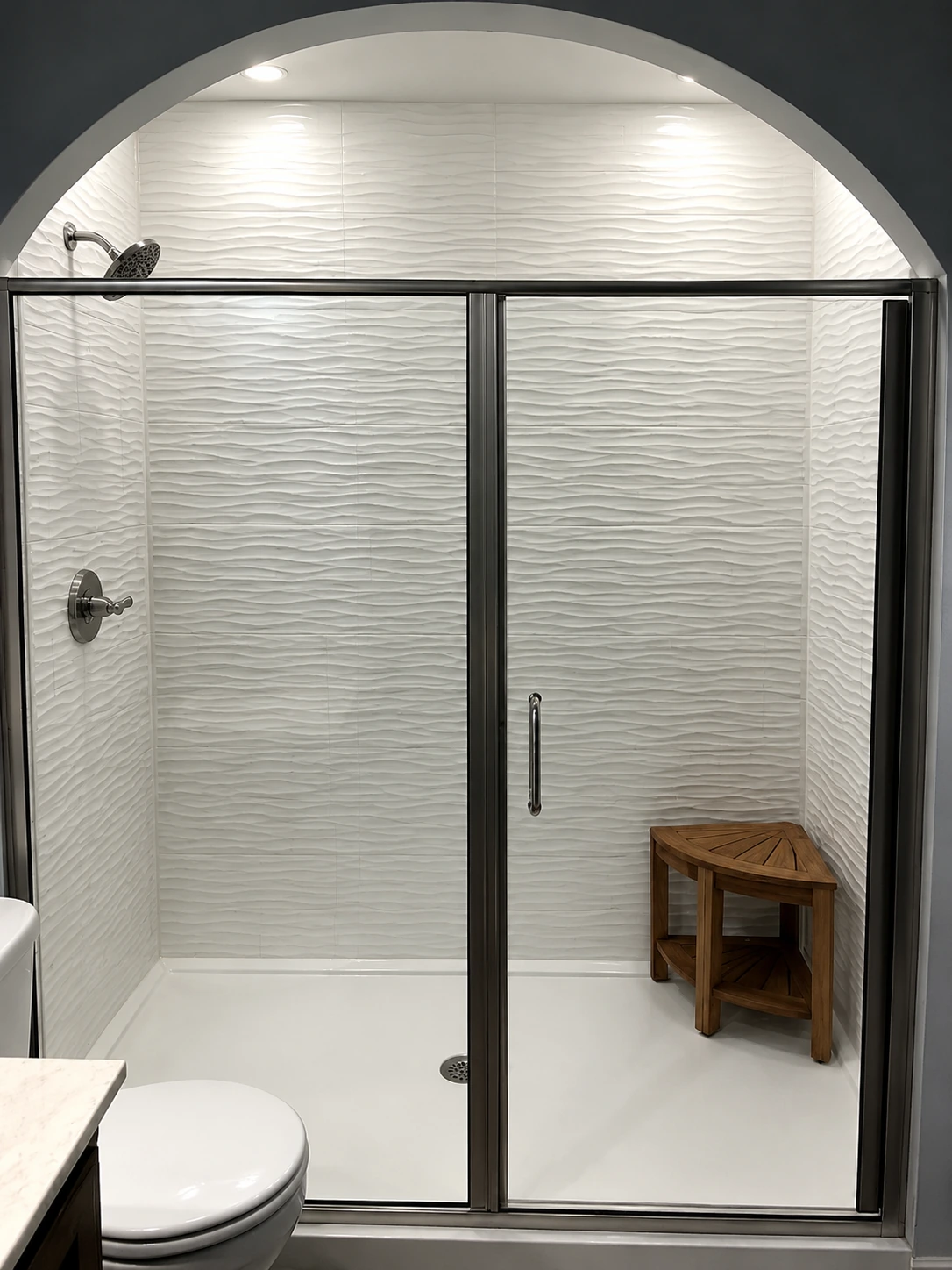 Arched walk-in shower with wave-textured white tile and a teak corner bench