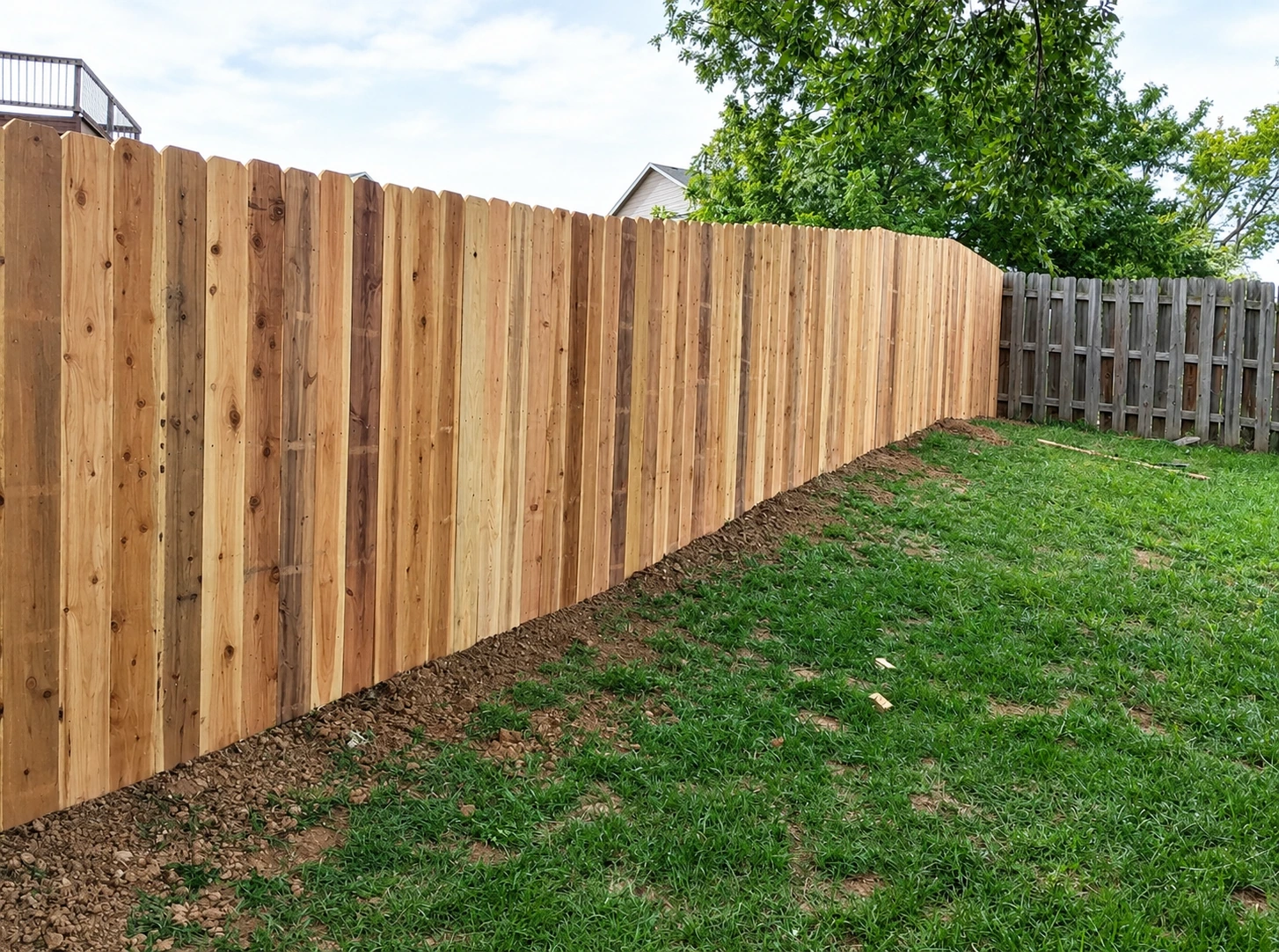 Long run of new cedar privacy fence following a sloped backyard