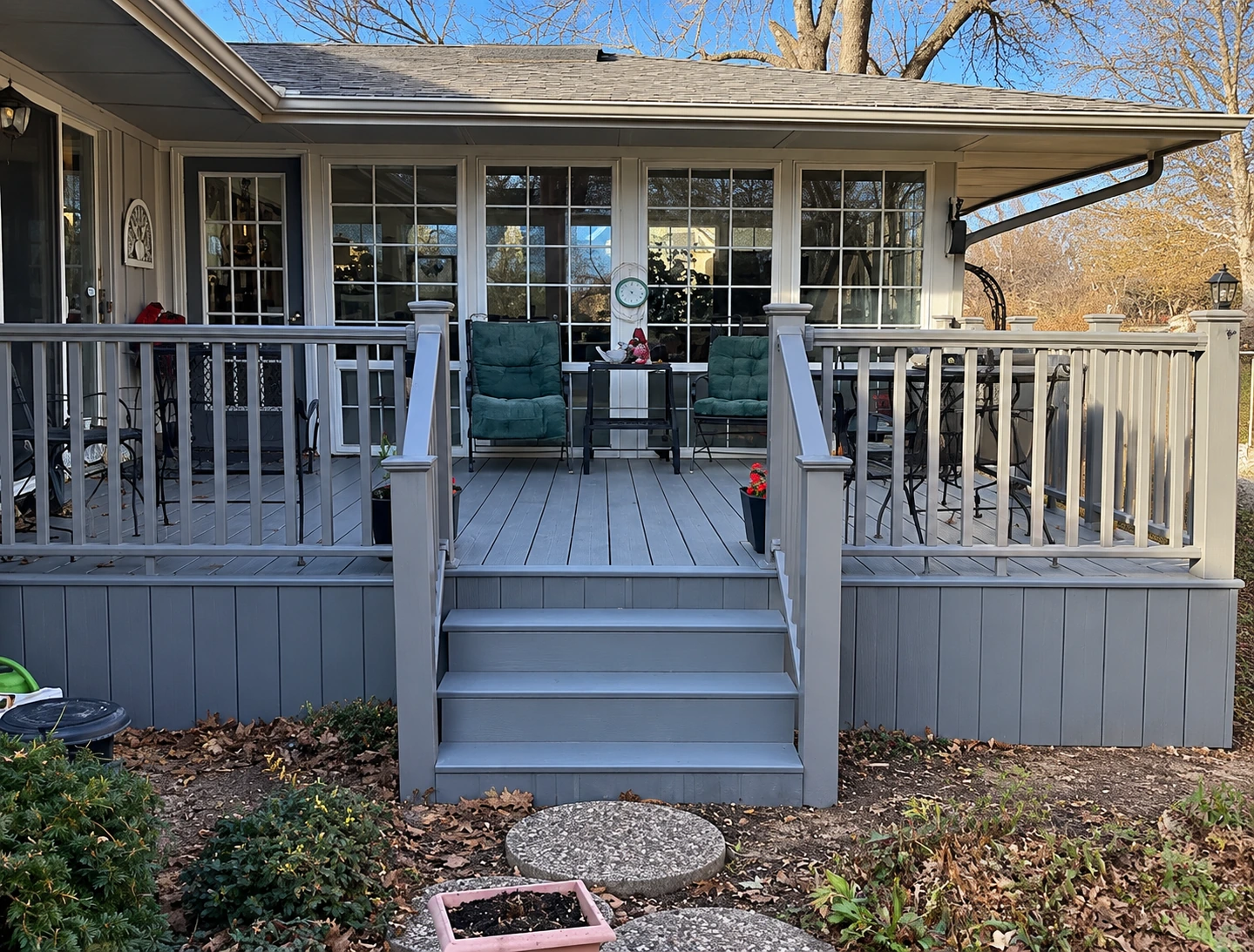 Grey-painted covered porch deck with railings and wide front steps